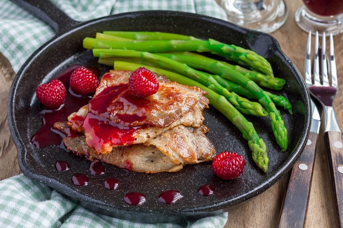Pork,Cutlets,With,Raspberry,Sauce,And,Asparagus,In,Iron,Cast