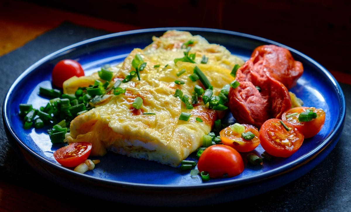 Omelette,With,Tomatoes,,Green,Onion,On,Blue,Plate.