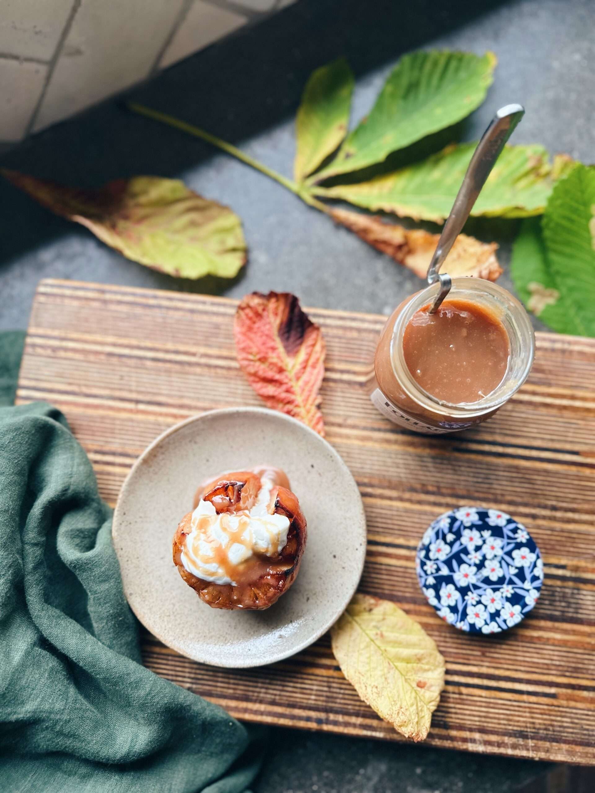 birds eye view looking at cooked apple on white plate with greek yogurt and irish cream liqueur topped on apple next to open jar of follain irish cream liqueur